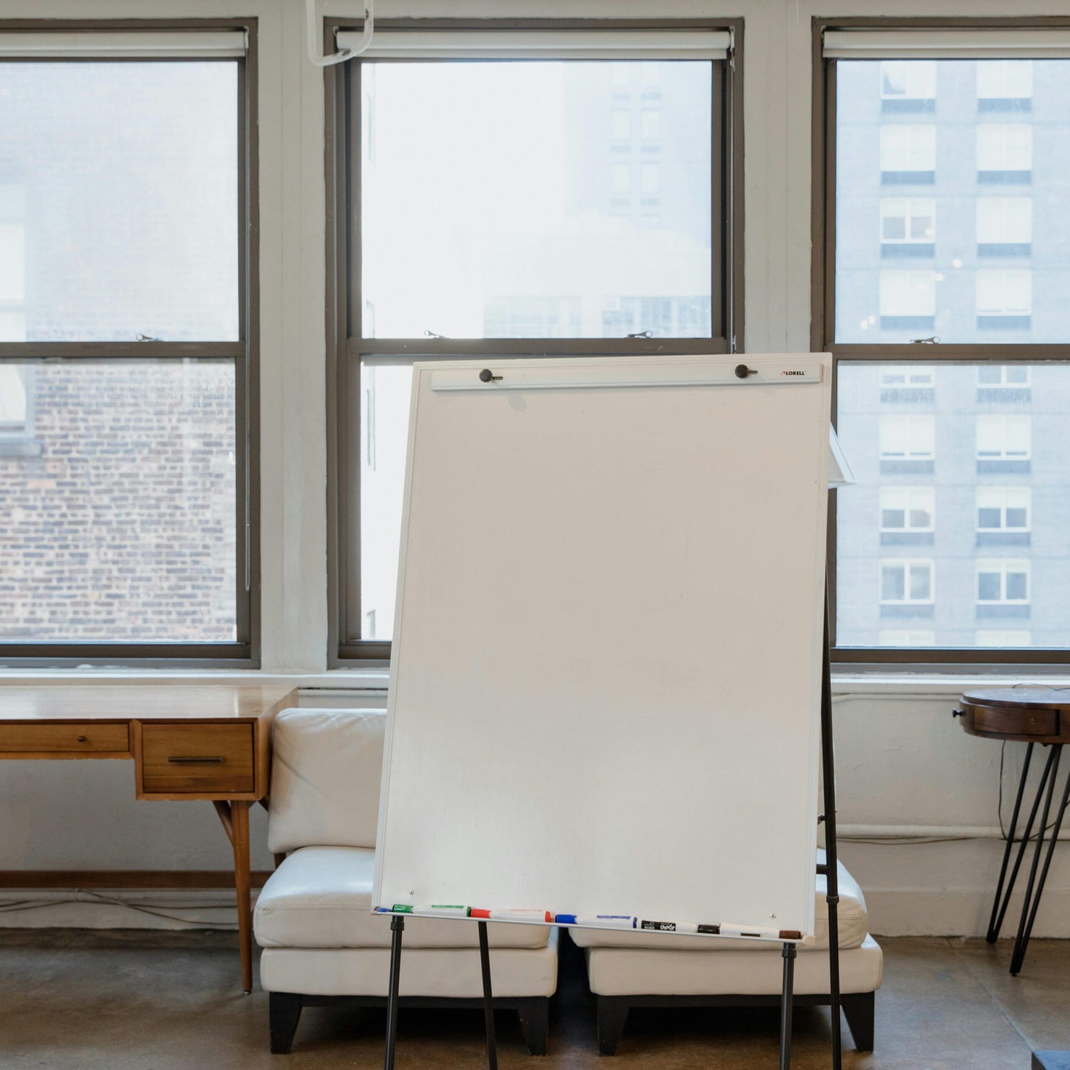 flipchart A white board and some chairs in front of windows.