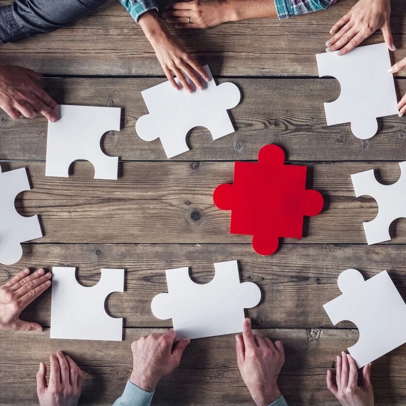 fm=f_xrZV2oN A group of people sitting around a table with puzzle pieces.