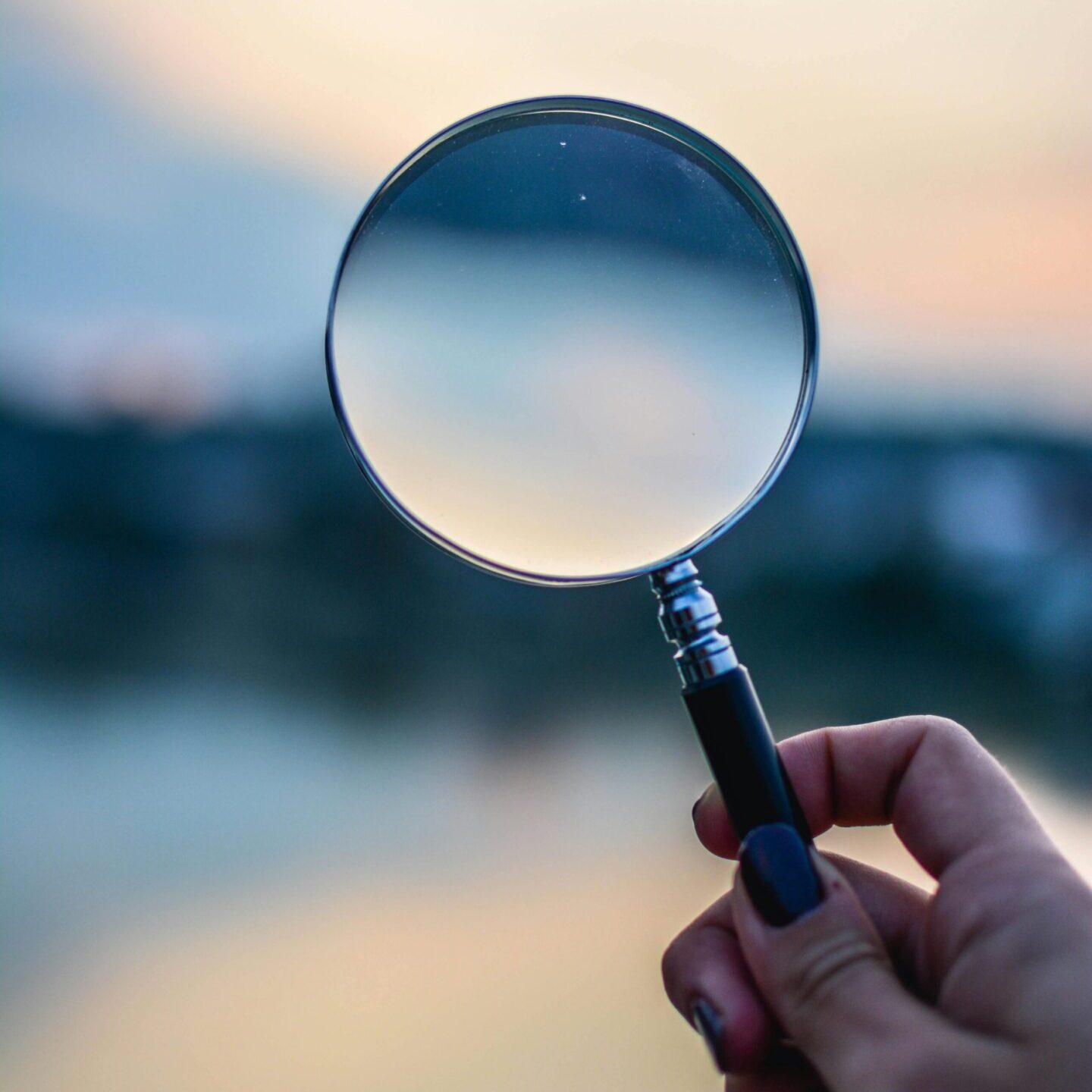 looking glass A person holding a magnifying glass in their hand.