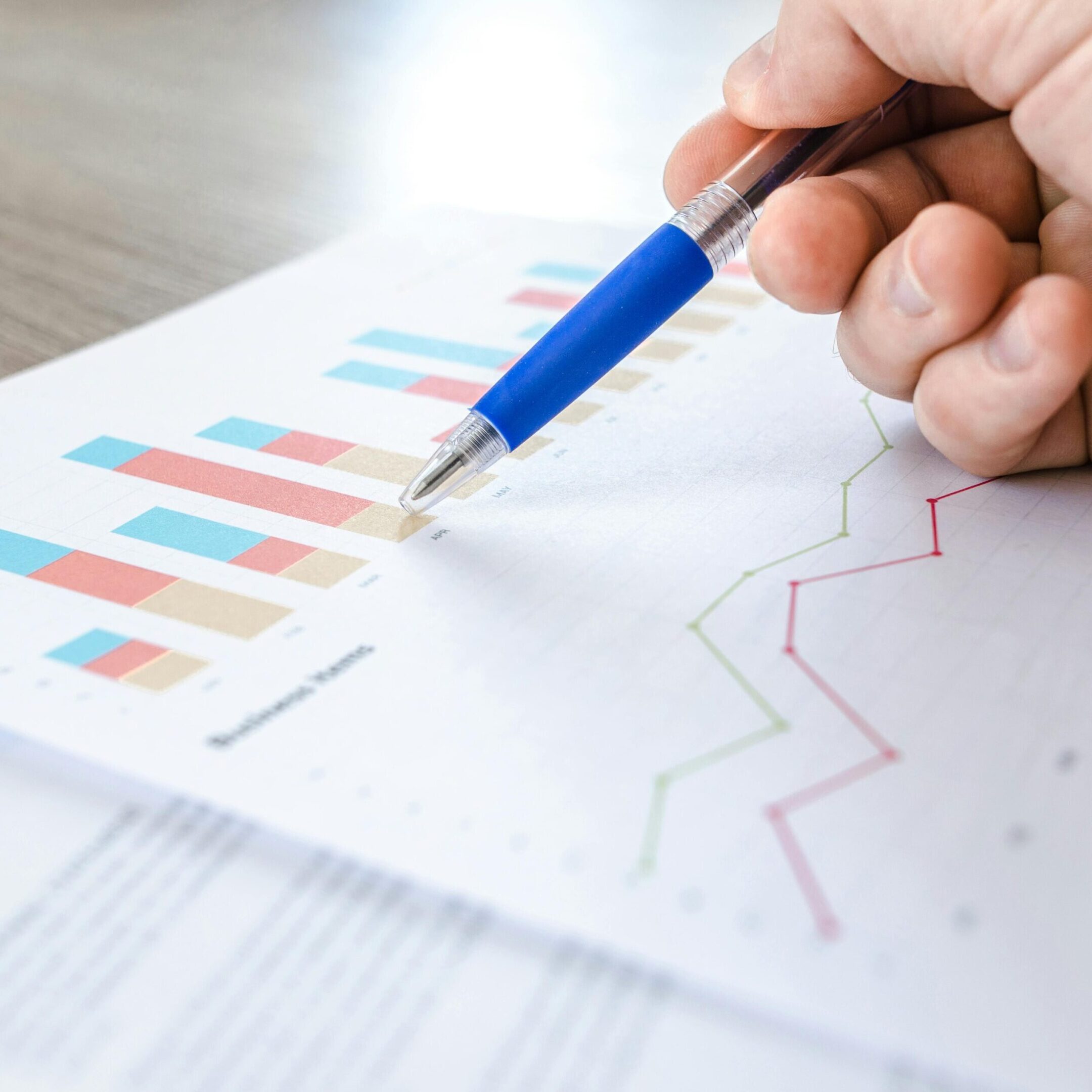 research A person is holding a pen and pointing to some graphs.